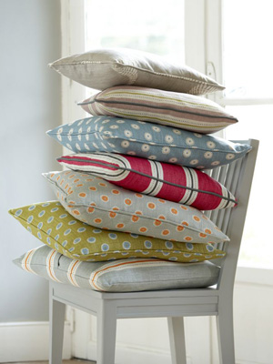 Handmade fabric cushions piled on top of a white wooden chair