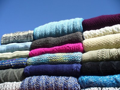 Pile of multi-coloured knitted jumpers