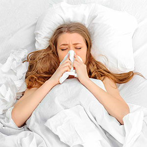 Woman in bed sneezing - Antibiotics: get the facts - Your health issues - Diet & wellbeing - allaboutyou.com