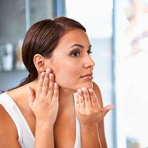 Woman looking at face in mirror - skincare - blemishes - fashion & beauty - allaboutyou.com
